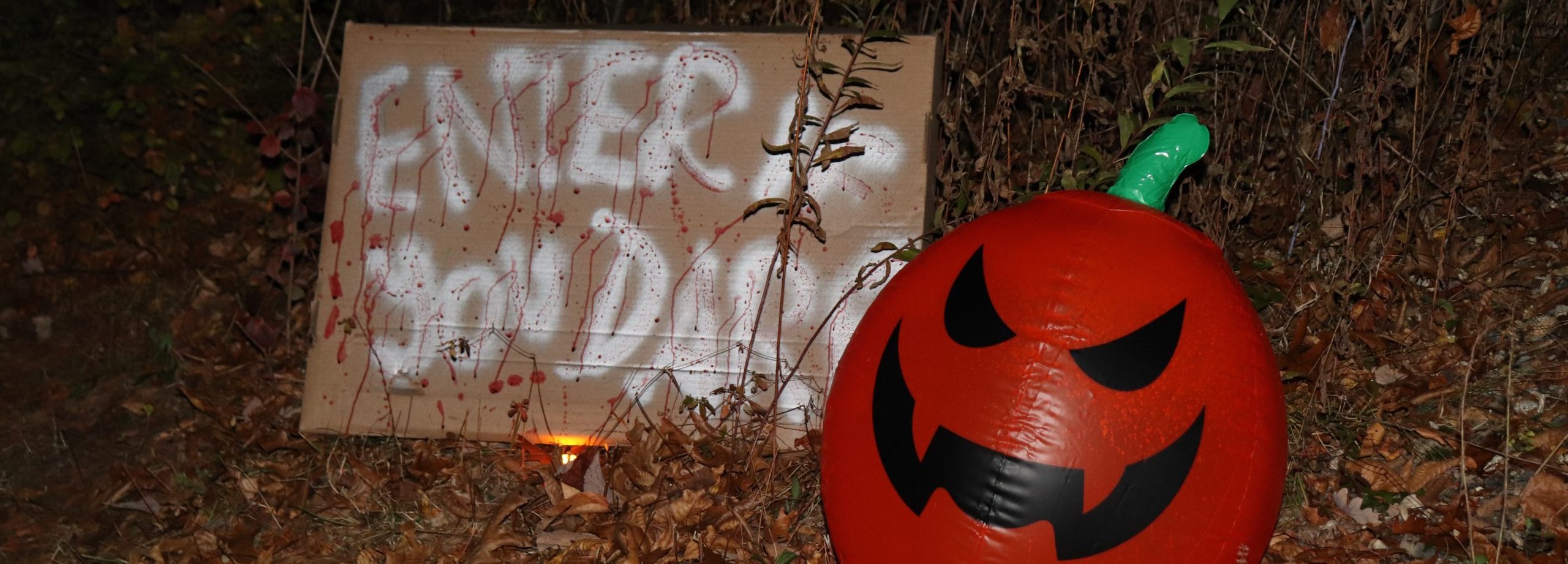 inflatable pumpkin with spray painted sign next to it that reads 'enter if you dare'