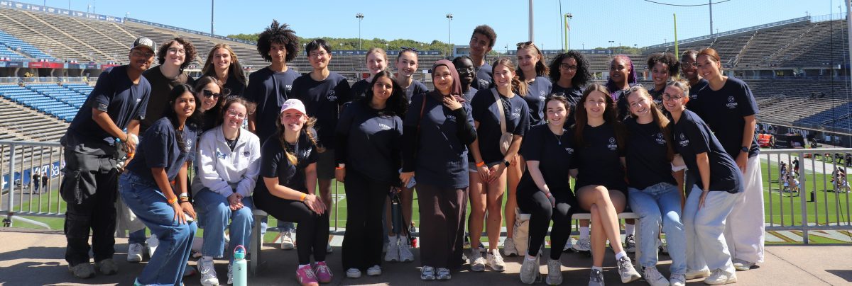 30 students smiling at a football game.