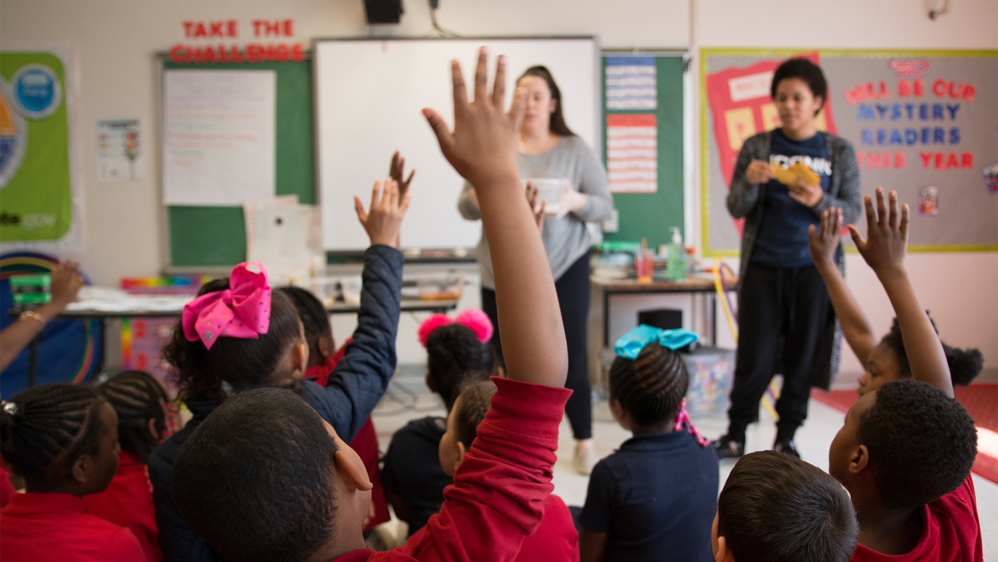 Children raising their hands during a Husky Nutrition & Sport class